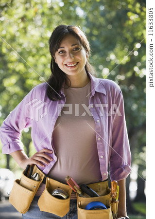 Hispanic woman wearing tool belt 11633805