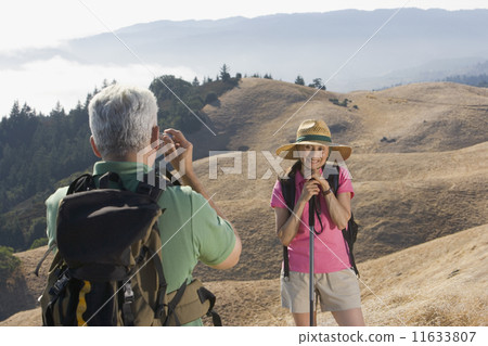 Senior man taking a picture of his wife on a hike Senior man taking a picture of his wife on a hike 11633807