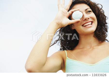Woman holding seashell over eye 11633826