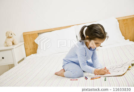 Mixed Race girl coloring on bed 11633830