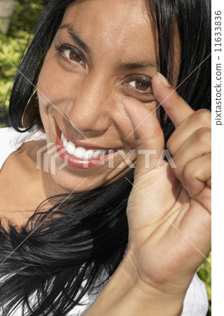 Hispanic woman holding out thumb and index finger Hispanic woman holding out thumb and index finger 11633836