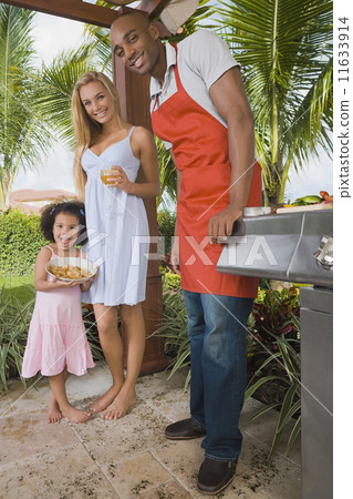 Mixed Race family barbecuing 11633914