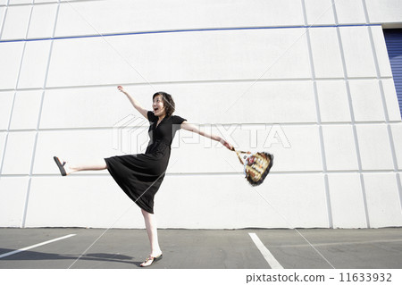 Asian woman kicking up leg in parking lot 11633932