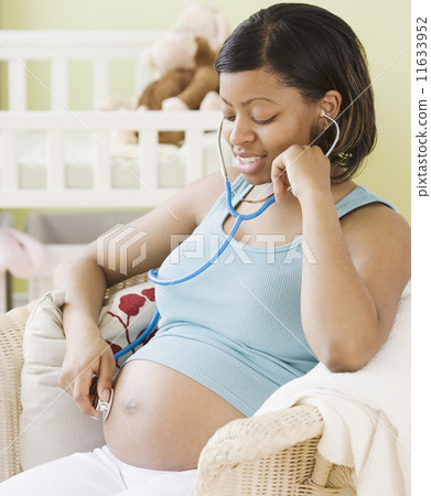 Pregnant African American woman listening to belly Pregnant African American woman listening to belly 11633952