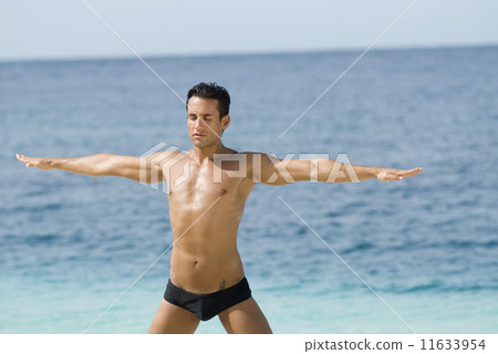 Hispanic man practicing yoga at beach Hispanic man practicing yoga at beach 11633954