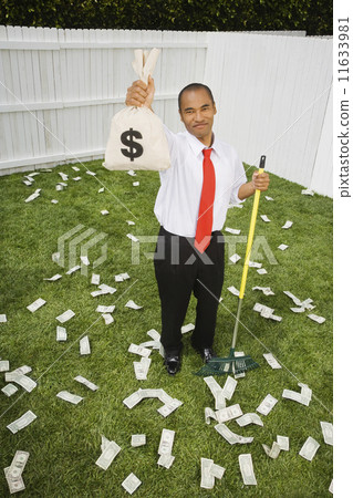 Mixed Race businessman raking up money 11633981