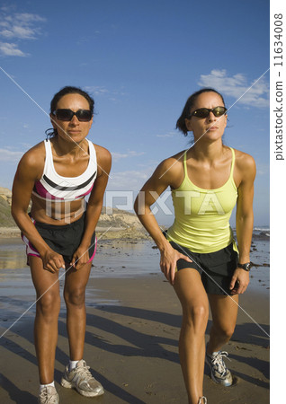 Hispanic female runners racing at beach 11634008