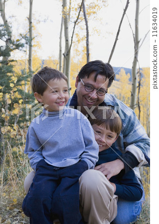 Hispanic father and sons in woods 11634019