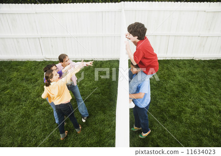 Mixed Race boys looking over fence at girls 11634023