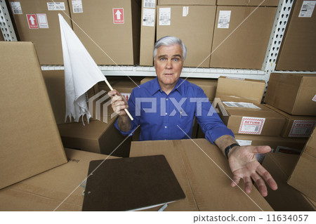 Businessman in warehouse waving white flag 11634057