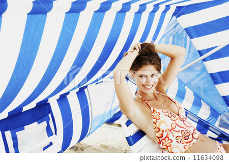 Young woman sitting under beach sun shade Young woman sitting under beach sun shade 11634098
