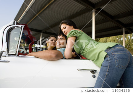Hispanic man with two women in convertible 11634156