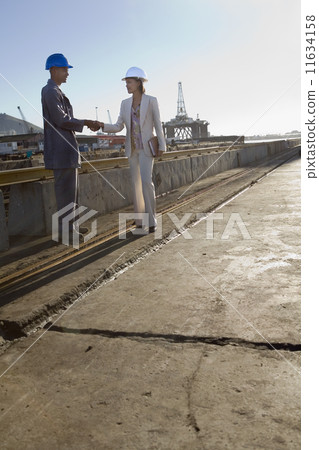 African American businesswoman and construction worker shaking hands 11634158