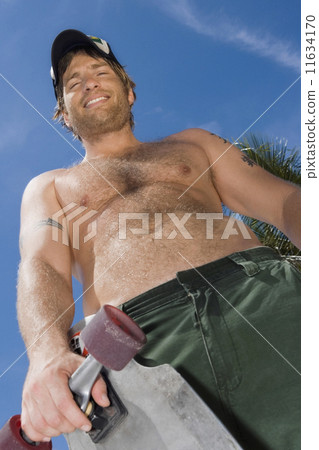 Hispanic man holding skateboard 11634170