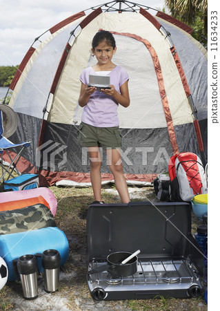 Hispanic girl surrounded by camping supplies 11634233