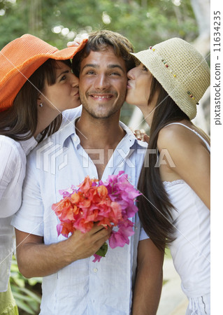 Two women kissing man on both cheeks Two women kissing man on both cheeks 11634235