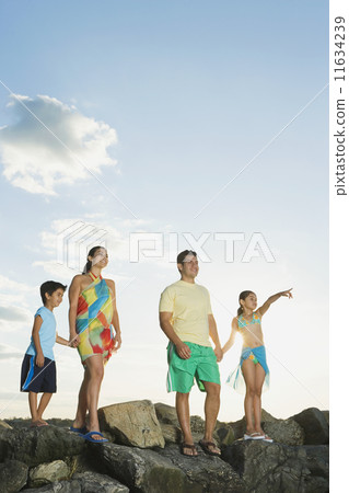 Hispanic family standing on rocks at beach Hispanic family standing on rocks at beach 11634239