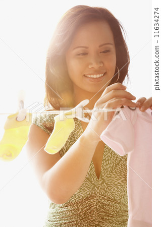 Asian woman hanging baby clothing on clothes line 11634274