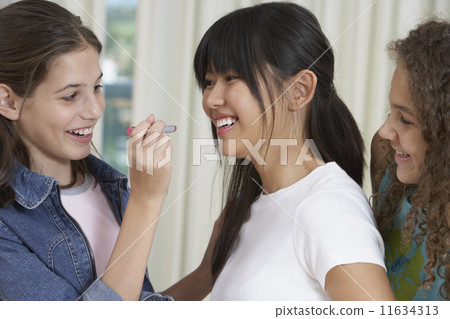 Teenaged girls applying lipstick Teenaged girls applying lipstick 11634313