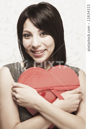 Hispanic woman hugging heart-shaped box Hispanic woman hugging heart-shaped box 11634315