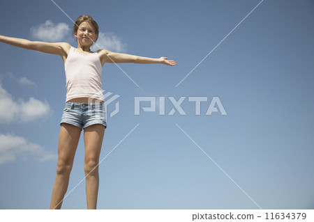 Teenage girl with arms outstretched under blue sky Teenage girl with arms outstretched under blue sky 11634379