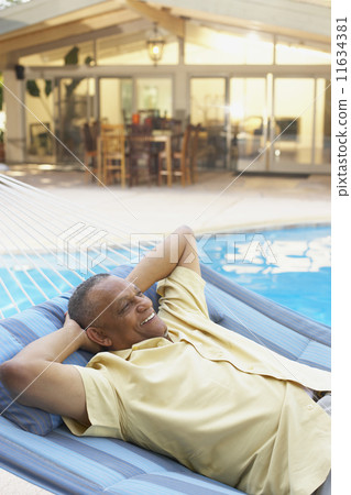 African man laying in hammock at poolside 11634381