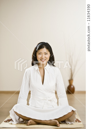 Asian woman sitting on meditation mat 11634390