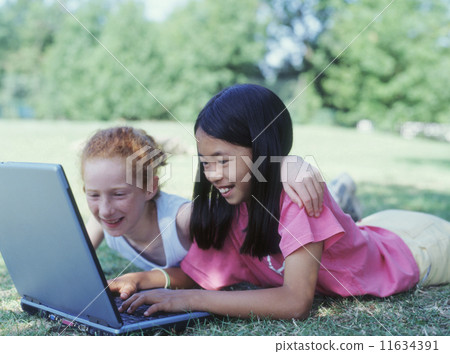 Two girls laying in park with laptop Two girls laying in park with laptop 11634391