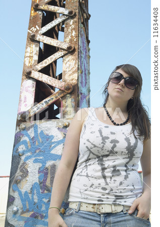 Young woman standing next to graffitied metal tower 11634408