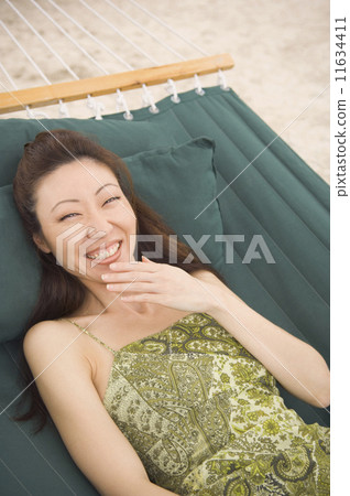 Asian woman laughing in hammock 11634411