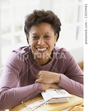 Middle-aged woman smiling for the camera at her desk 11634481