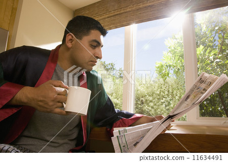 Hispanic man reading newspaper 11634491