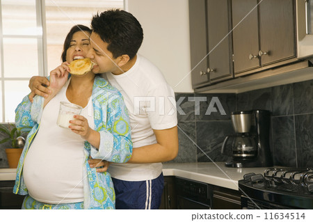 Pregnant couple in pajamas in kitchen Pregnant couple in pajamas in kitchen 11634514