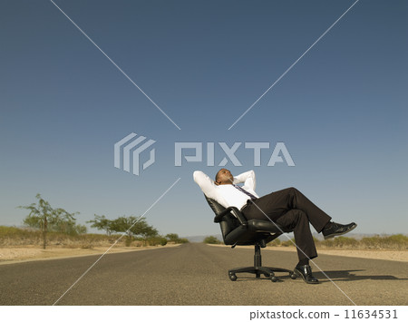 African businessman sitting in middle of road 11634531
