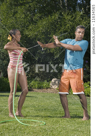 Multi-ethnic couple playing with hose Multi-ethnic couple playing with hose 11634565
