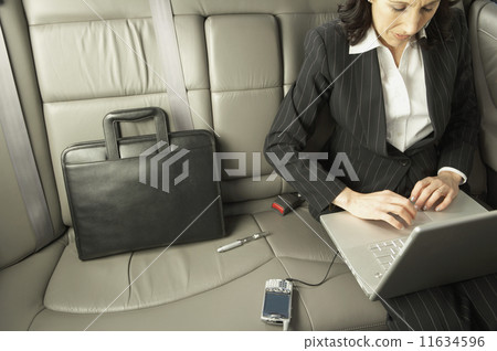 Businesswoman working in the backseat of a car  11634596