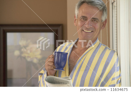 Hispanic man holding coffee and newspaper 11634675