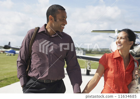 Multi-ethnic couple walking away from airplane Multi-ethnic couple walking away from airplane 11634685