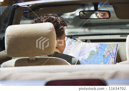 Senior Hispanic woman looking at map in car 11634702