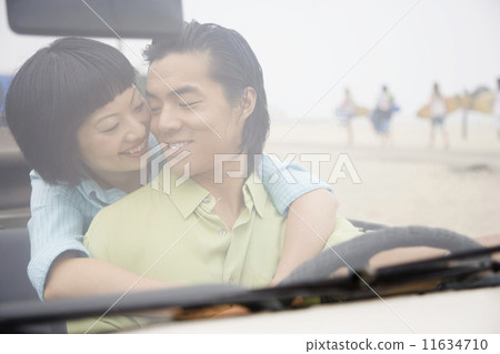 Asian couple hugging in convertible 11634710