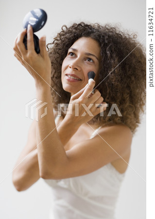 Studio shot of Hispanic woman applying makeup 11634721