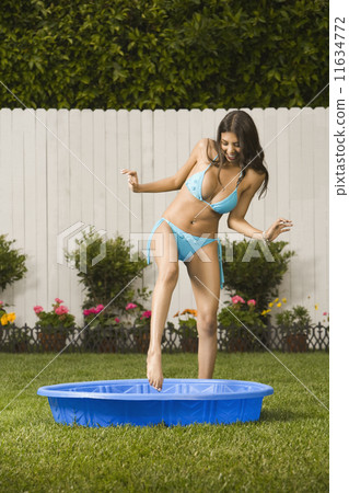 Hispanic woman stepping into kiddie pool Hispanic woman stepping into kiddie pool 11634772