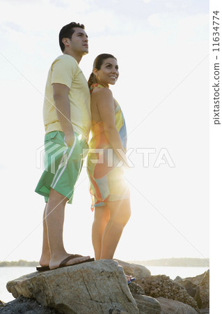 Hispanic couple standing on rocks at beach Hispanic couple standing on rocks at beach 11634774