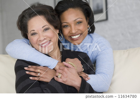 African mother and adult daughter hugging 11634780