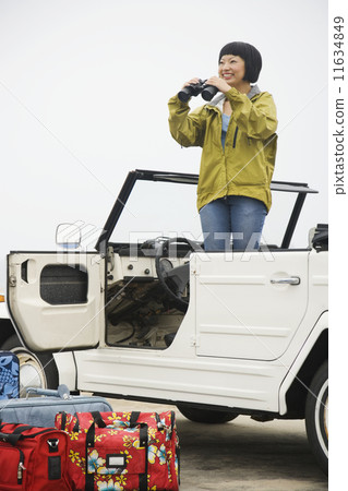 Asian woman with binoculars in convertible 11634849