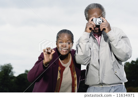 Senior African couple taking photograph outdoors Senior African couple taking photograph outdoors 11634971