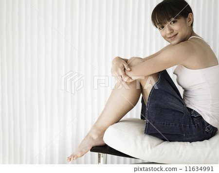 Portrait of teenage girl sitting with arms wrapped around legs 11634991