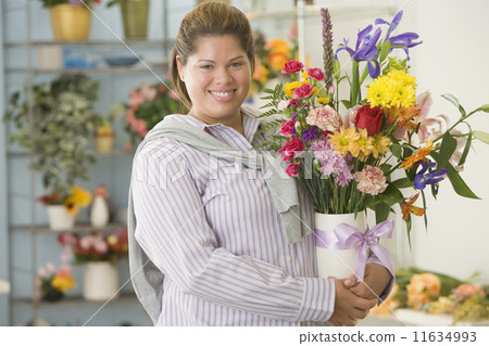 Hispanic woman holding flowers in vase 11634993