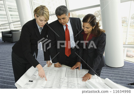 Multi-ethnic businesspeople looking at blueprints 11634998