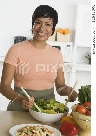 Portrait of Hispanic woman tossing salad 11635000
